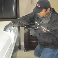 Bed bug inspection technician checking a mattress and bed frame for signs of infestation in Charlotte, NC